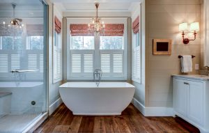 New bathroom with wood floor and white tub | Featured image for the Blog on the Best Blinds for Bathroom Use from Cosmopolitan Shutters.
