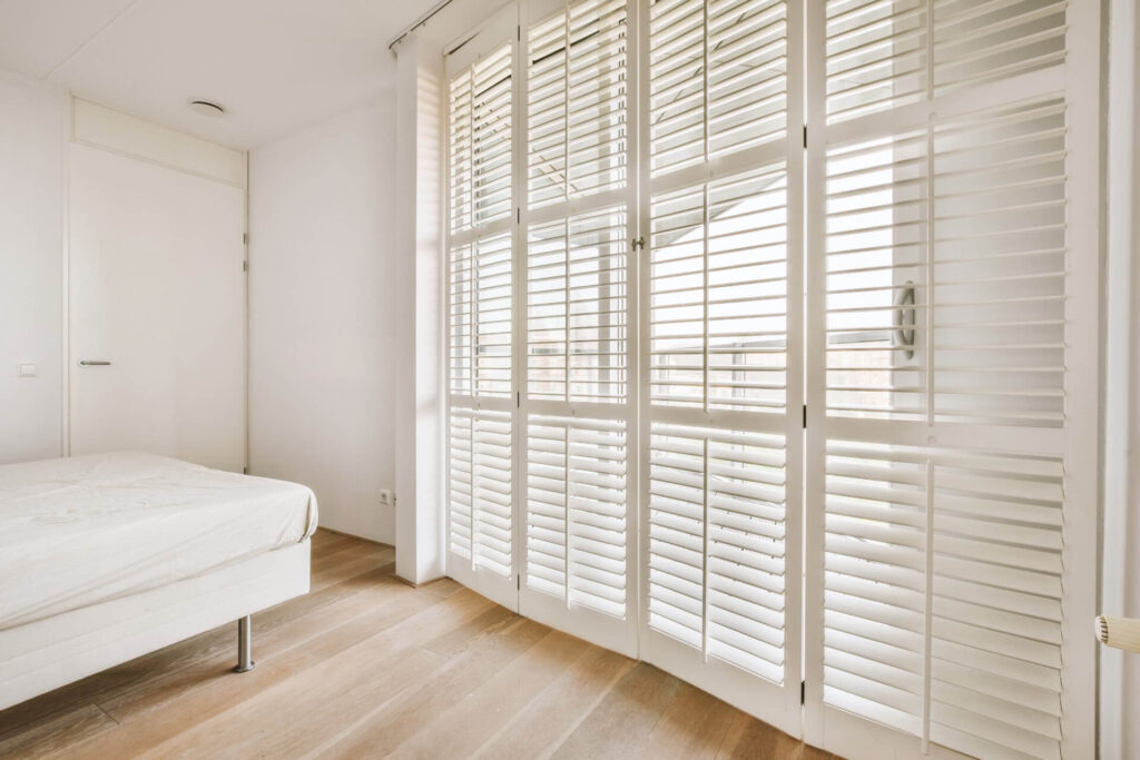 Bedroom with plantation shutters | Featured image for the How to Clean Plantation Shutters Blog by Cosmopolitan Shutters.